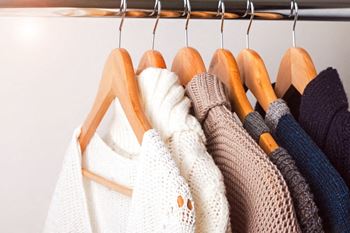 Sweaters hanging in closet on wooden hangers